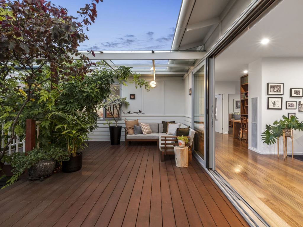 Cozy outdoor wooden deck with seating and greenery.