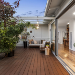 Cozy outdoor wooden deck with seating and greenery.