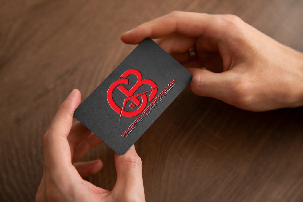 A hand holding a black business card with a red logo.