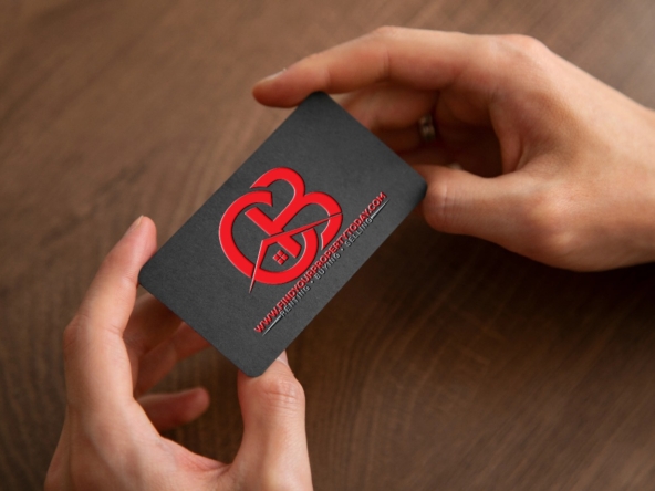 A hand holding a black business card with a red logo.